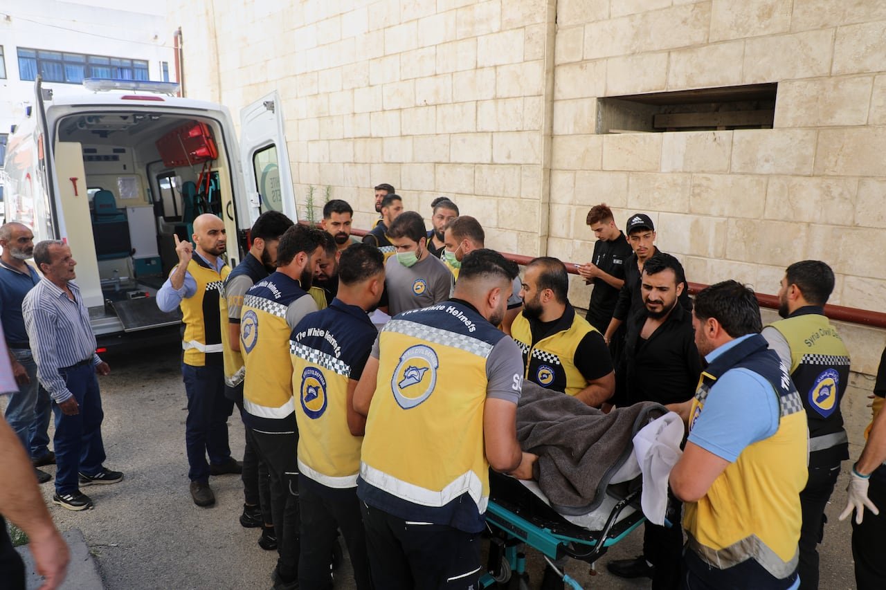 Civil defence volunteer members gather around a body of someone on a stretcher.